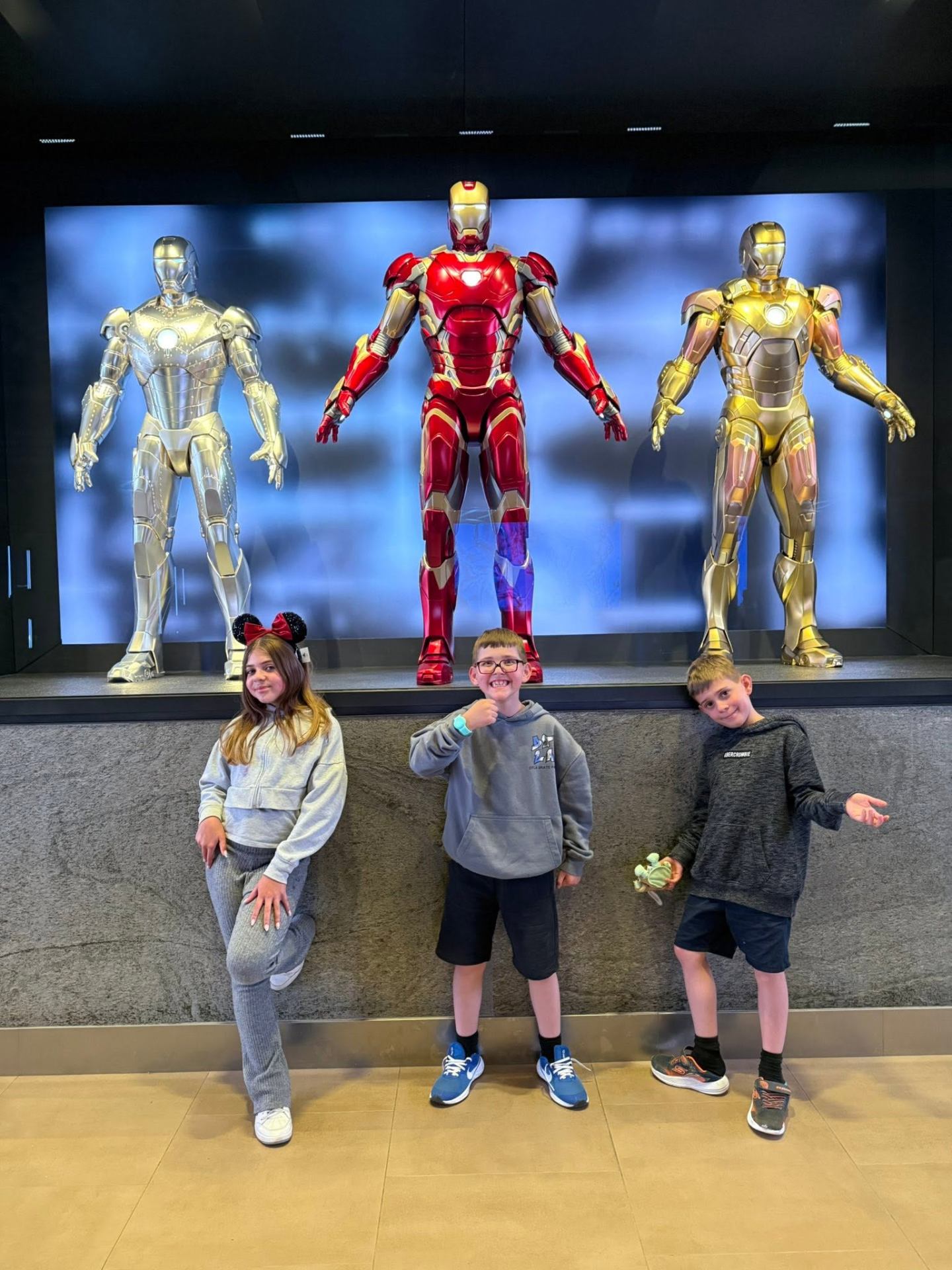 Kids posing with Iron Man statues